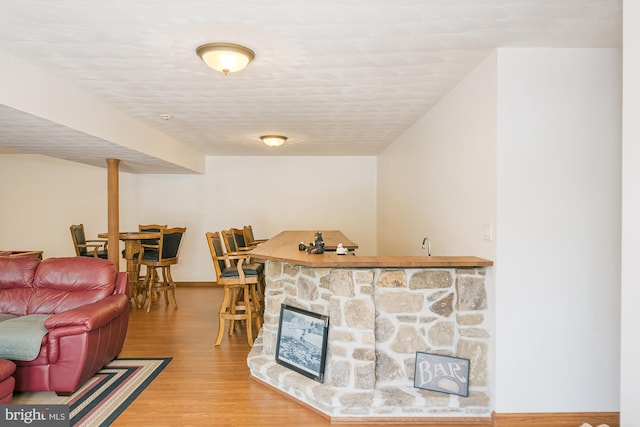 living room featuring bar area, a textured ceiling, and hardwood / wood-style floors