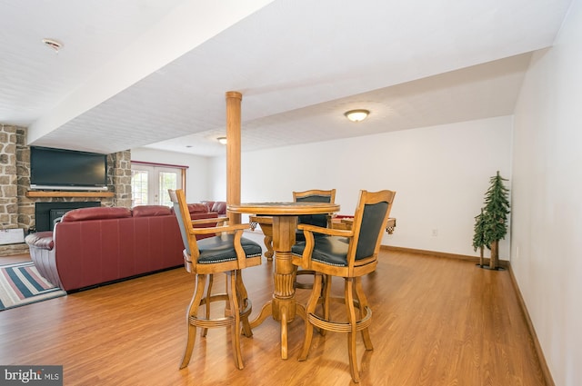 dining area with light hardwood / wood-style floors and a stone fireplace