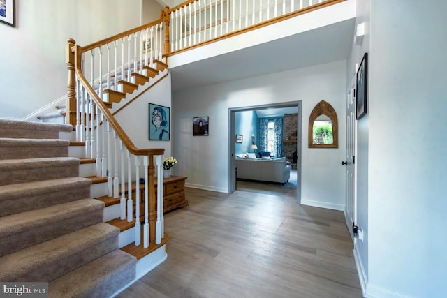 entrance foyer featuring stairs, a high ceiling, baseboards, and wood finished floors