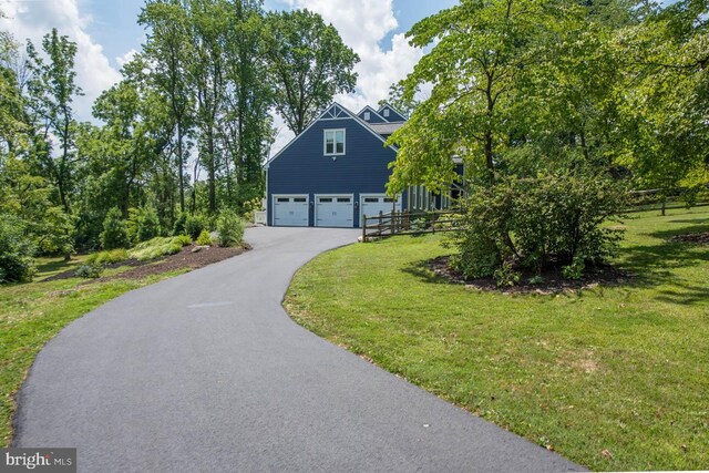 view of front of house with aphalt driveway, an attached garage, and a front lawn