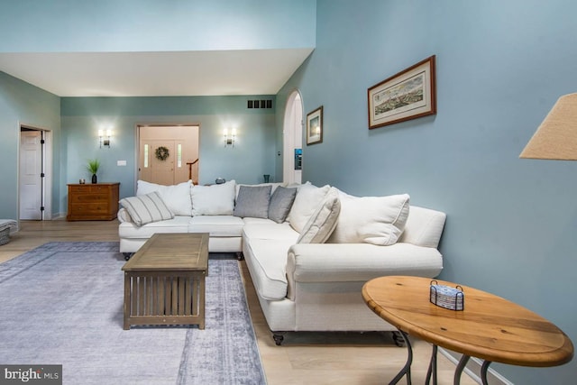 living room featuring light wood finished floors, visible vents, and arched walkways