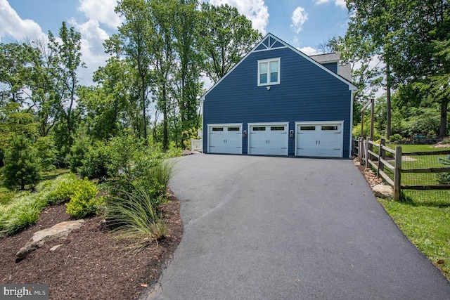 view of home's exterior featuring a garage, driveway, and fence