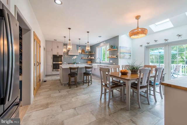 dining area with a skylight, recessed lighting, and stone finish flooring