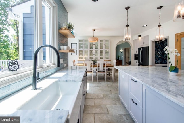 kitchen with open shelves, arched walkways, white cabinetry, and freestanding refrigerator