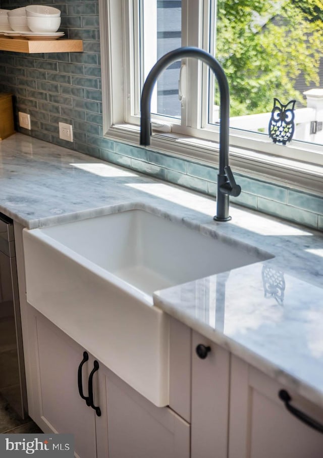 room details with a sink, open shelves, light stone counters, and tasteful backsplash