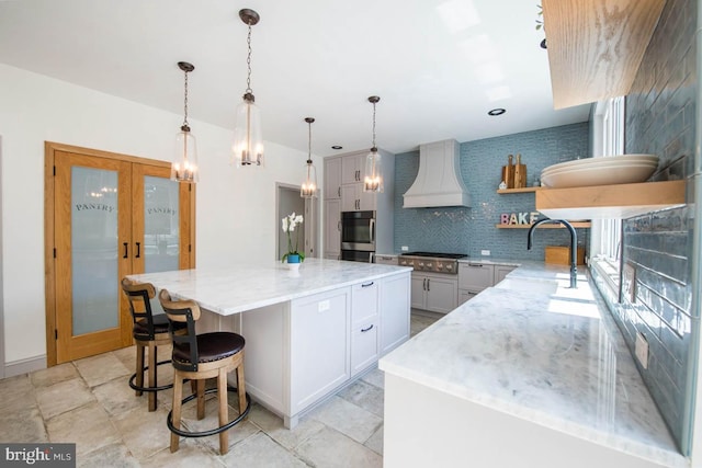 kitchen with custom range hood, light stone counters, decorative backsplash, french doors, and open shelves