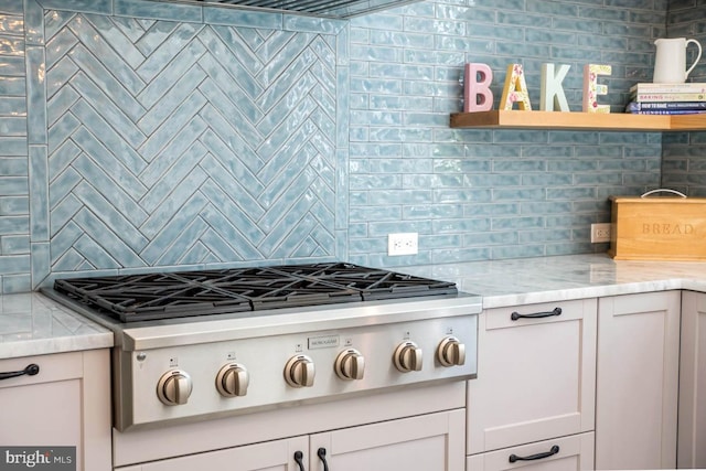 kitchen with open shelves, light stone countertops, backsplash, and stainless steel gas cooktop