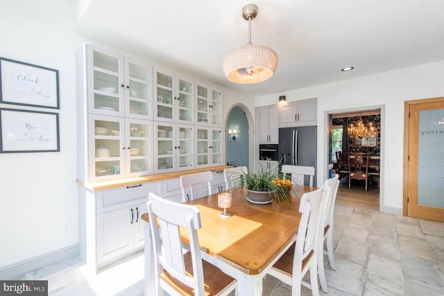 dining room featuring arched walkways, recessed lighting, and baseboards