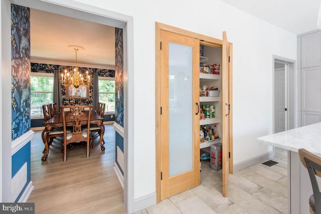 dining space featuring light wood finished floors, baseboards, and an inviting chandelier