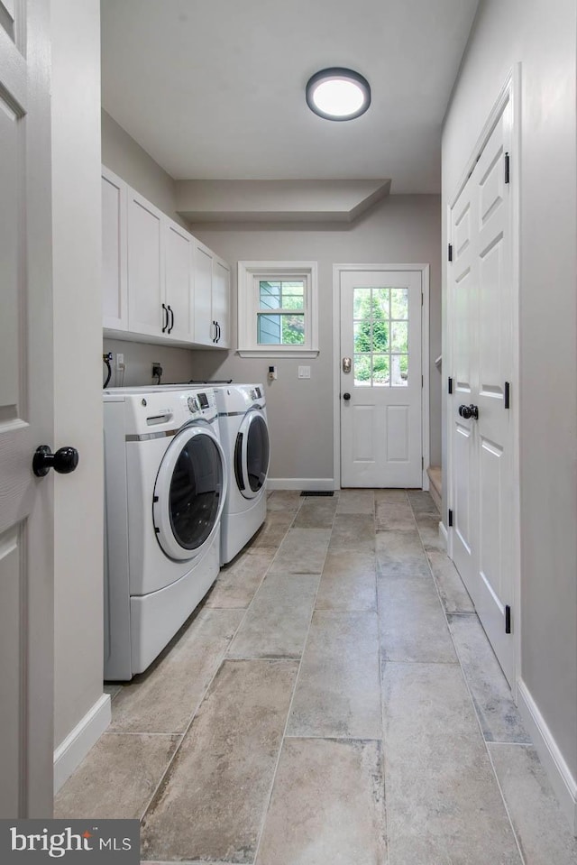 clothes washing area with cabinet space, baseboards, and washing machine and clothes dryer