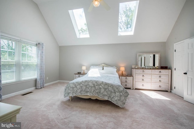 carpeted bedroom featuring visible vents, high vaulted ceiling, a ceiling fan, a skylight, and baseboards