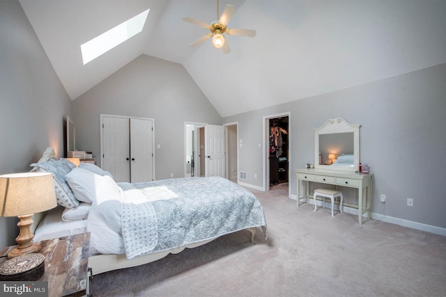 bedroom with light colored carpet, baseboards, high vaulted ceiling, and a skylight