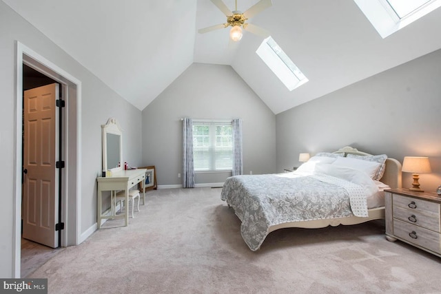 carpeted bedroom with vaulted ceiling with skylight, baseboards, and ceiling fan