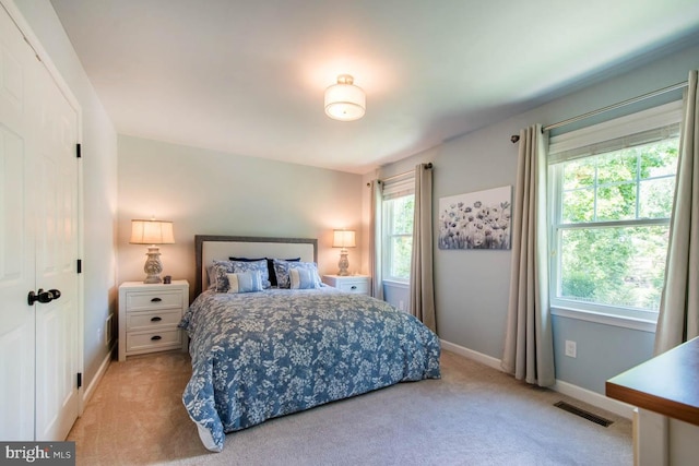 bedroom with visible vents, light carpet, and baseboards