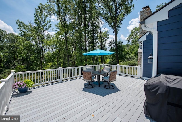 deck with outdoor dining area and a grill