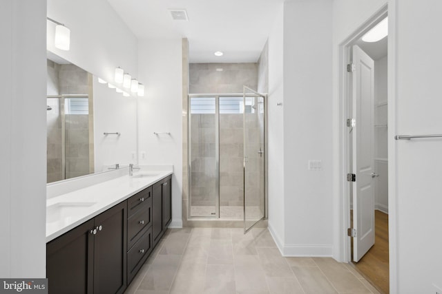 bathroom with a shower with shower door, vanity, and tile patterned flooring