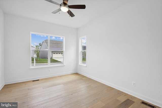 spare room with light wood-type flooring, ceiling fan, and plenty of natural light