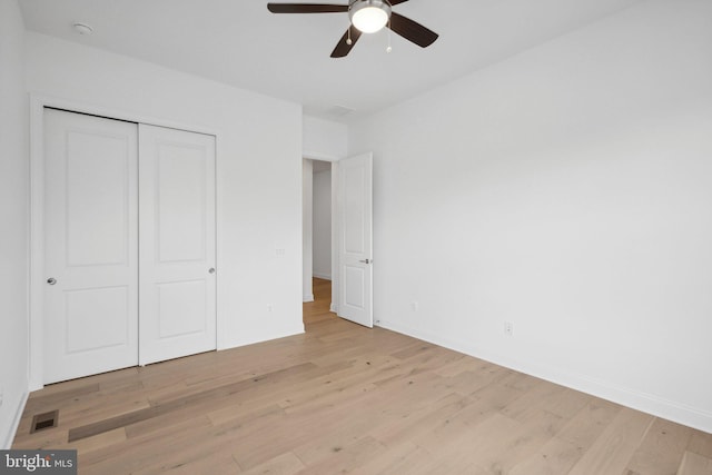 unfurnished bedroom featuring ceiling fan, a closet, and light hardwood / wood-style flooring