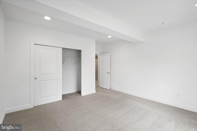 unfurnished bedroom with a closet and light colored carpet