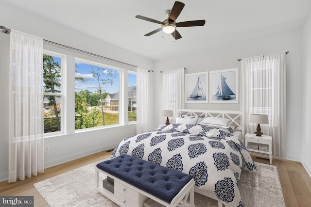 bedroom with ceiling fan, multiple windows, and light hardwood / wood-style floors