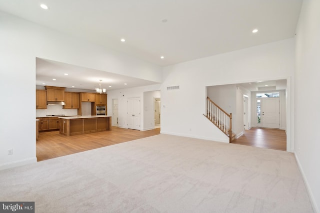 unfurnished living room with a chandelier and light hardwood / wood-style flooring