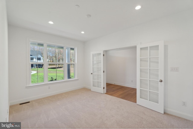 spare room featuring light colored carpet and french doors