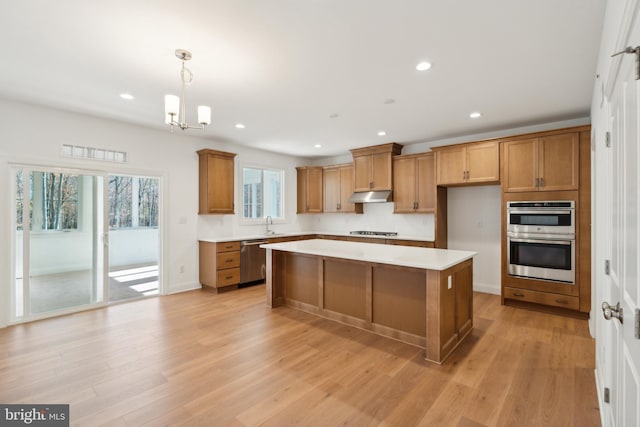 kitchen featuring a center island, hanging light fixtures, stainless steel appliances, light hardwood / wood-style flooring, and a chandelier