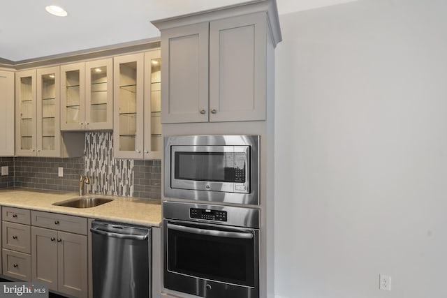 kitchen featuring gray cabinetry, decorative backsplash, sink, and appliances with stainless steel finishes