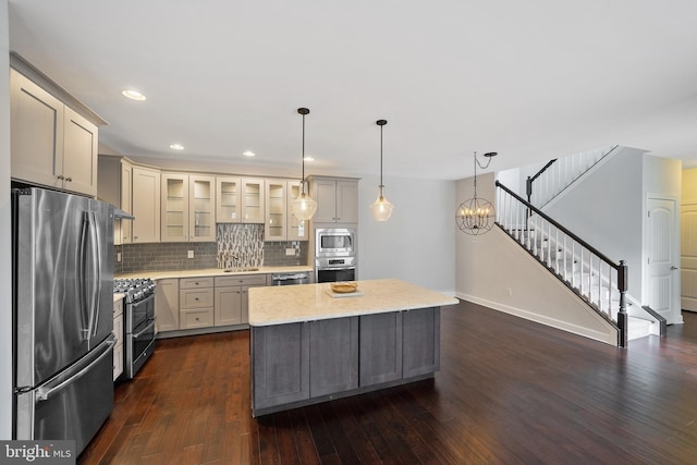 kitchen with tasteful backsplash, dark hardwood / wood-style floors, decorative light fixtures, a kitchen island, and appliances with stainless steel finishes