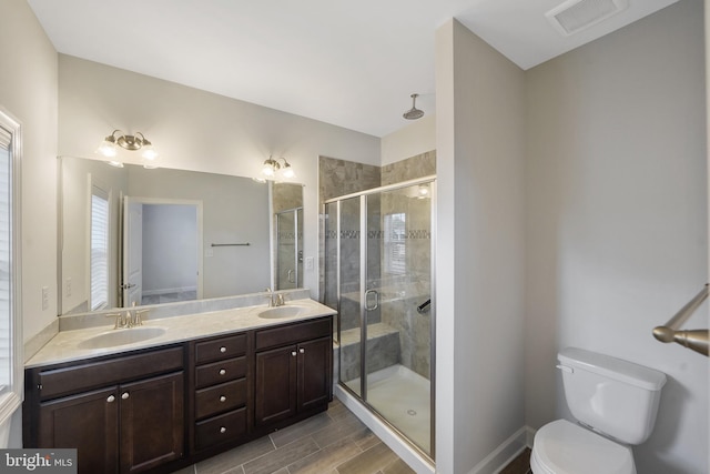 bathroom with vanity, toilet, and a shower with door