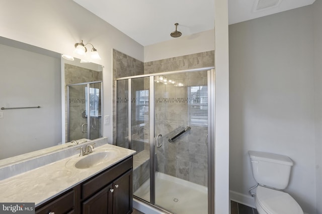 bathroom featuring vanity, toilet, and a shower with shower door