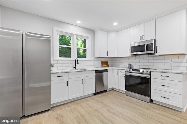 kitchen featuring sink, stainless steel appliances, light stone counters, white cabinets, and light wood-type flooring