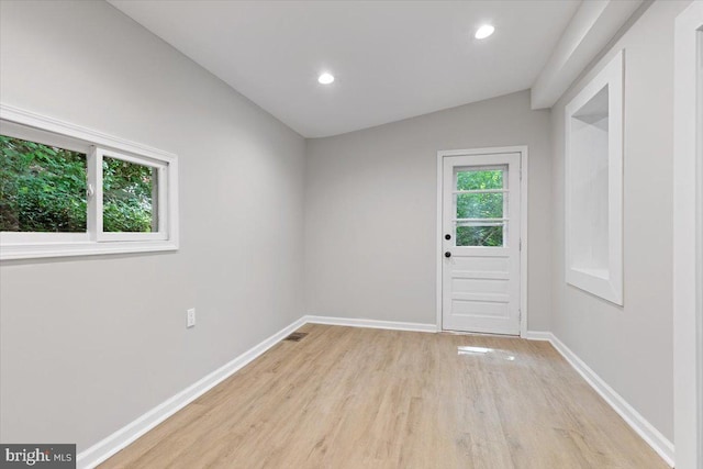 unfurnished room with vaulted ceiling and light hardwood / wood-style flooring