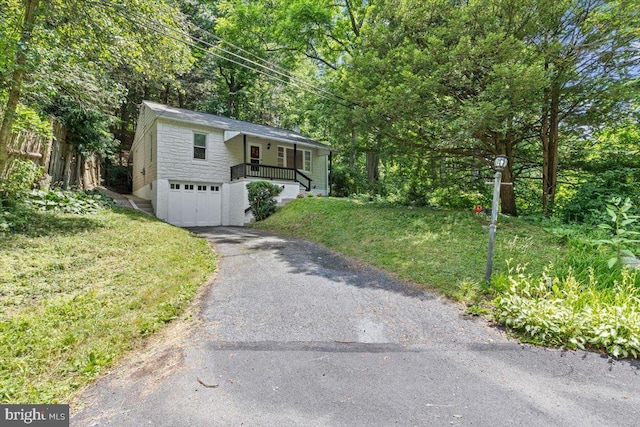 view of front facade featuring covered porch, a garage, and a front lawn