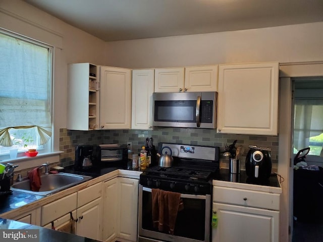 kitchen featuring backsplash, sink, white cabinets, and stainless steel appliances