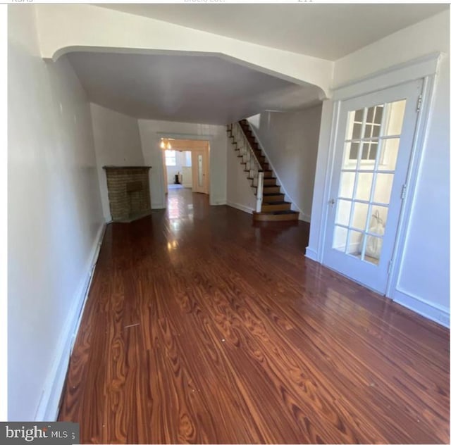 unfurnished living room featuring a fireplace and dark wood-type flooring