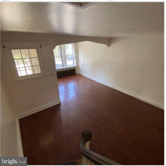 unfurnished room with lofted ceiling, dark hardwood / wood-style floors, and radiator heating unit