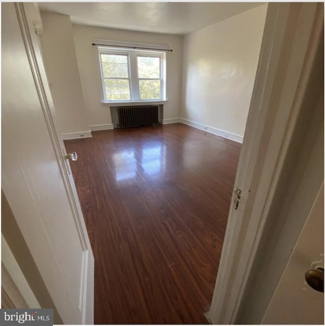 empty room featuring radiator heating unit and dark wood-type flooring