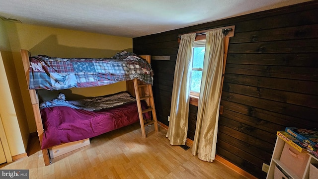 bedroom featuring hardwood / wood-style floors and wood walls