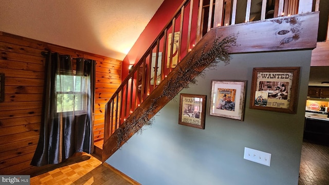 stairway with parquet floors, a textured ceiling, and wooden walls