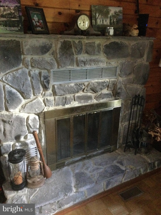 details with a stone fireplace and wooden walls