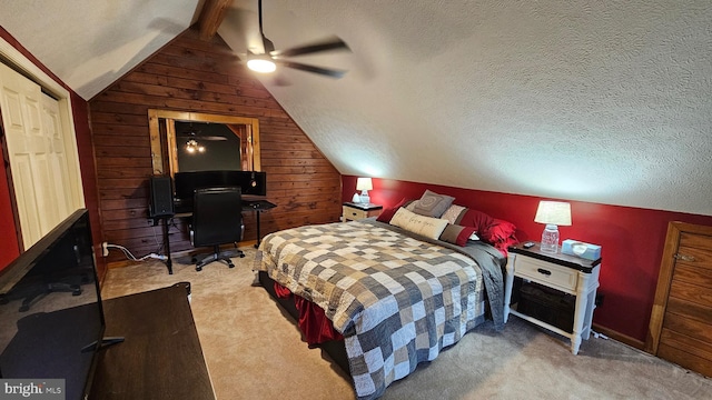 carpeted bedroom with a textured ceiling, vaulted ceiling with beams, ceiling fan, and wooden walls