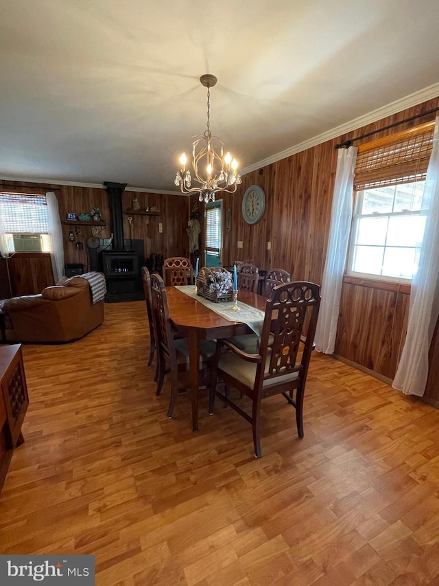 dining area with a chandelier, crown molding, a wood stove, and light hardwood / wood-style floors