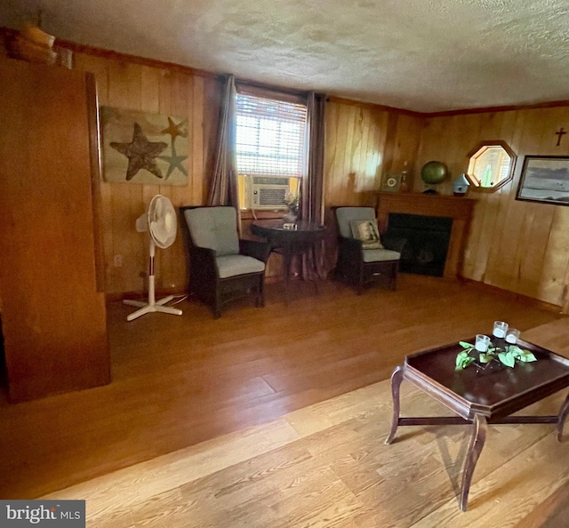 living area with light hardwood / wood-style floors, a textured ceiling, wood walls, and cooling unit