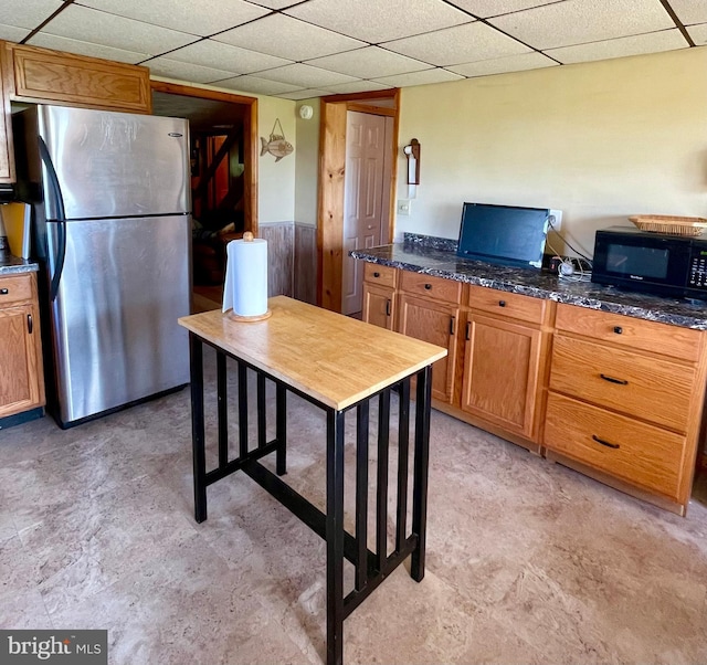 kitchen with dark stone countertops and stainless steel refrigerator