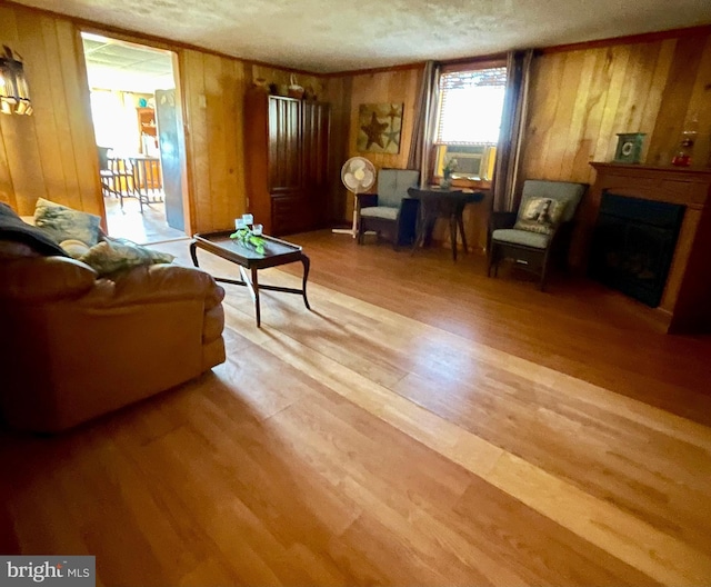 living room with a textured ceiling, light hardwood / wood-style flooring, and wood walls