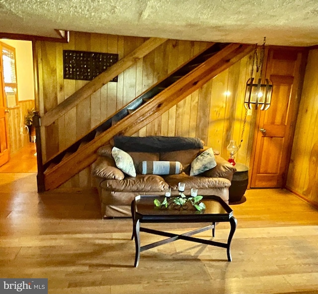 living room featuring hardwood / wood-style flooring, a textured ceiling, and wood walls