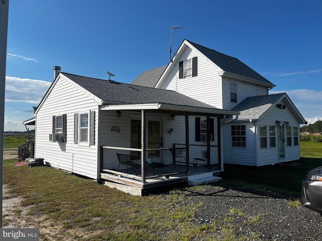 rear view of property featuring a lawn and a porch