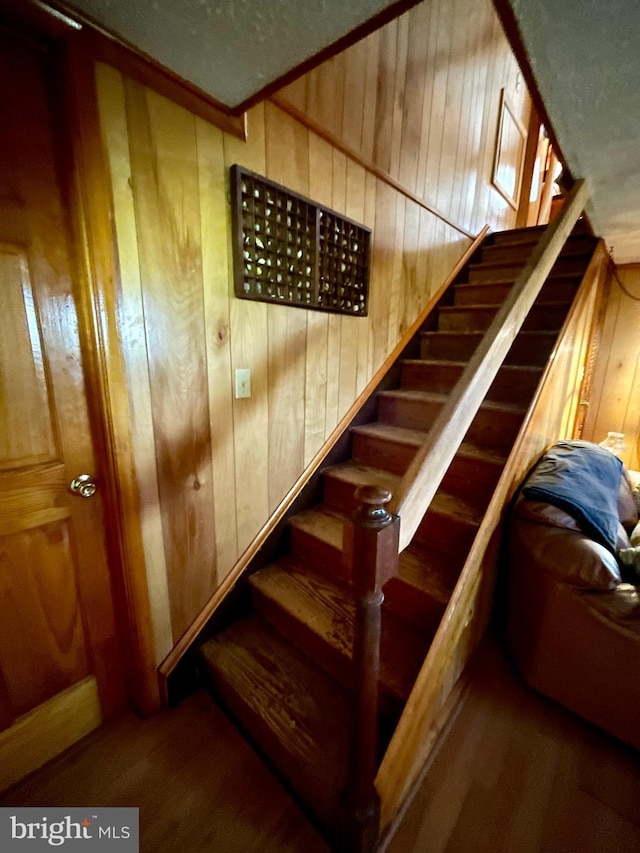 staircase featuring a mail area, wood-type flooring, and wood walls