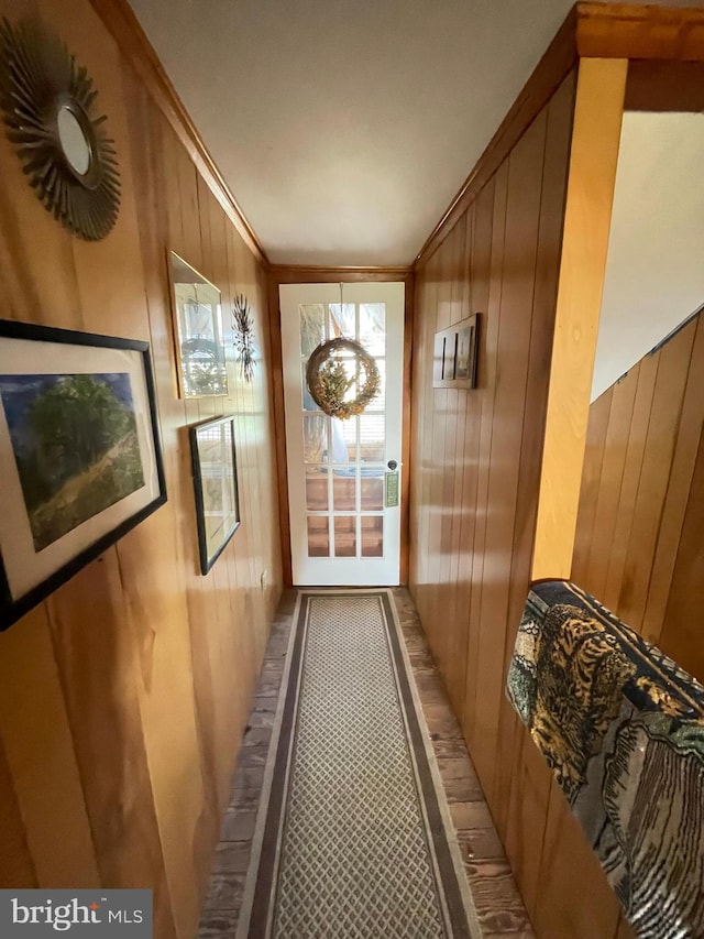 doorway to outside with wooden walls and ornamental molding